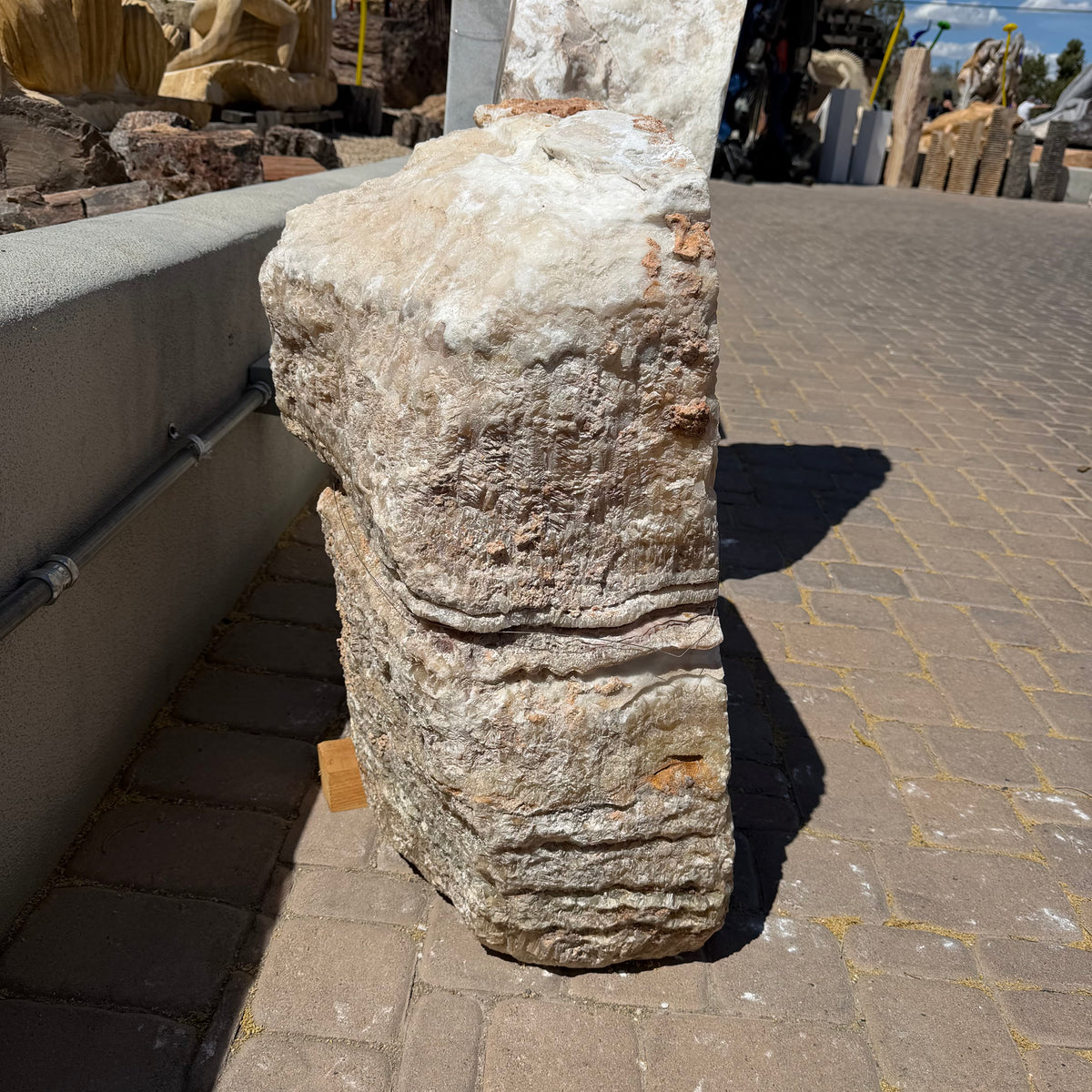 Side profile of serpentine onyx boulder fountain with natural layered surface in a stone yard