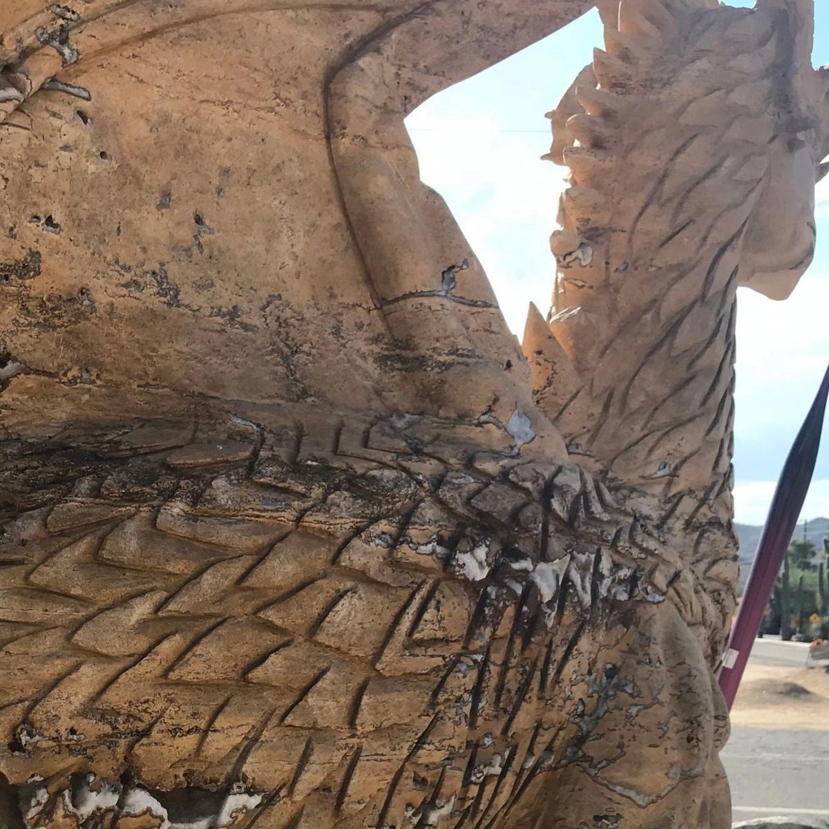 Close-up of tan travertine dragon's scaled body and wing showing natural quartz pockets
