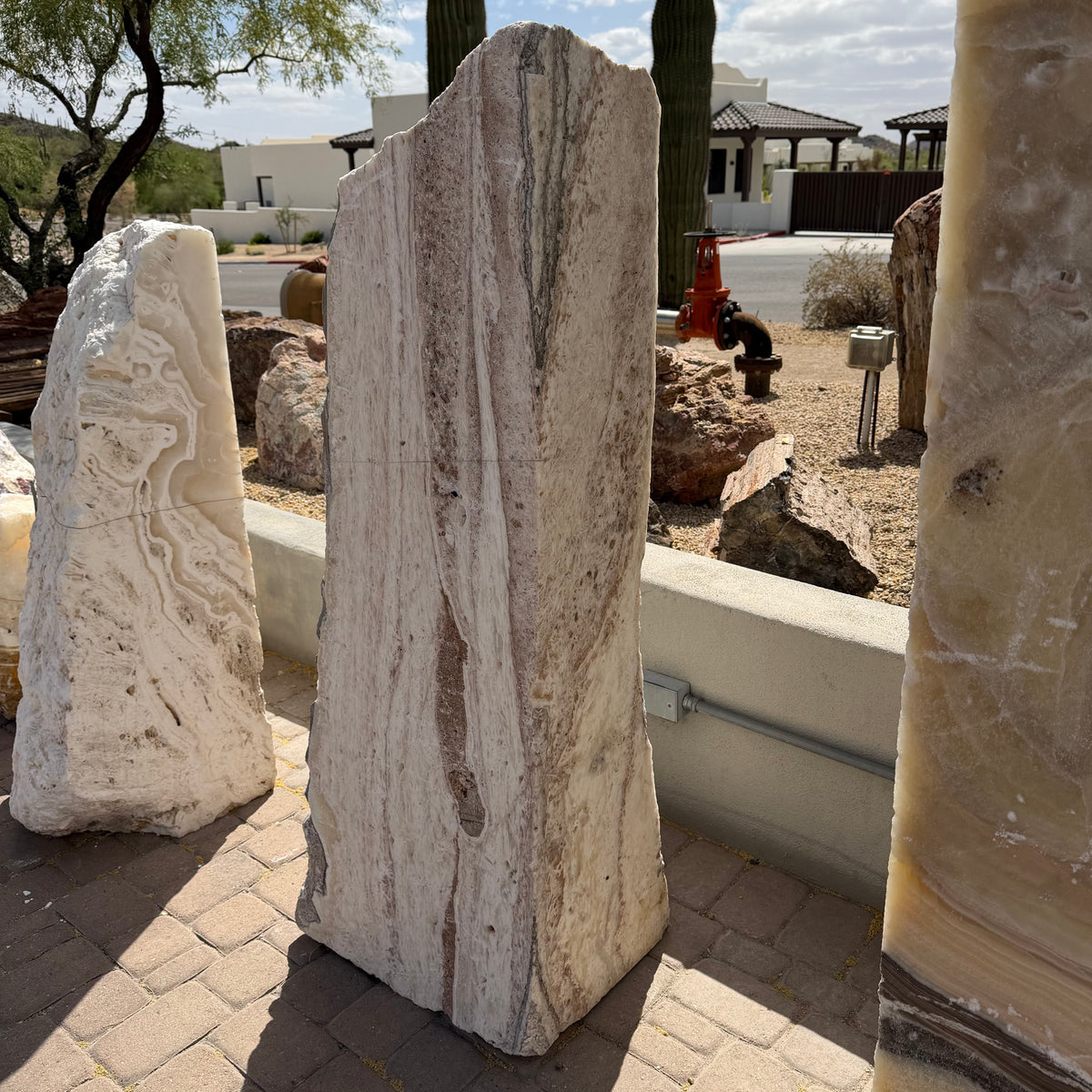 White travertine onyx fountain vertical block with red bands standing among onyx monoliths, desert backdrop