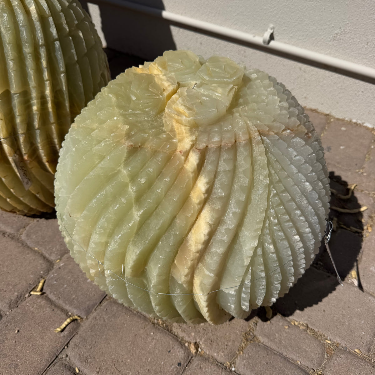 Carved green Talan onyx barrel cactus sculpture fountain beside a second cactus in sunlight