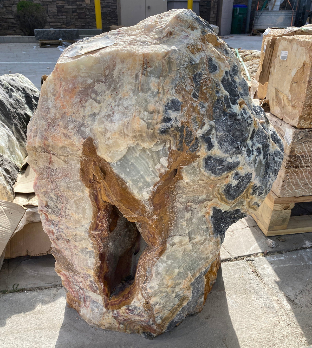 Green Talan Onyx rustic rock fountain with natural stone texture and a hollowed center, displayed outdoors on a concrete s...