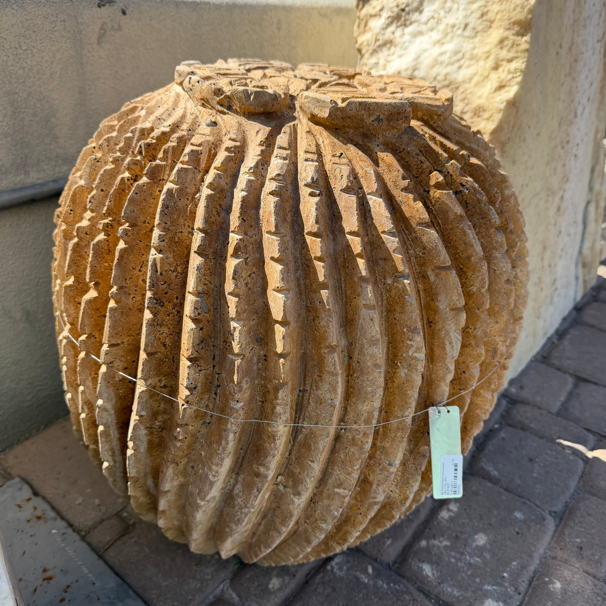 Full round red travertine barrel cactus carving with hanging price tag in the outdoor gallery yard
