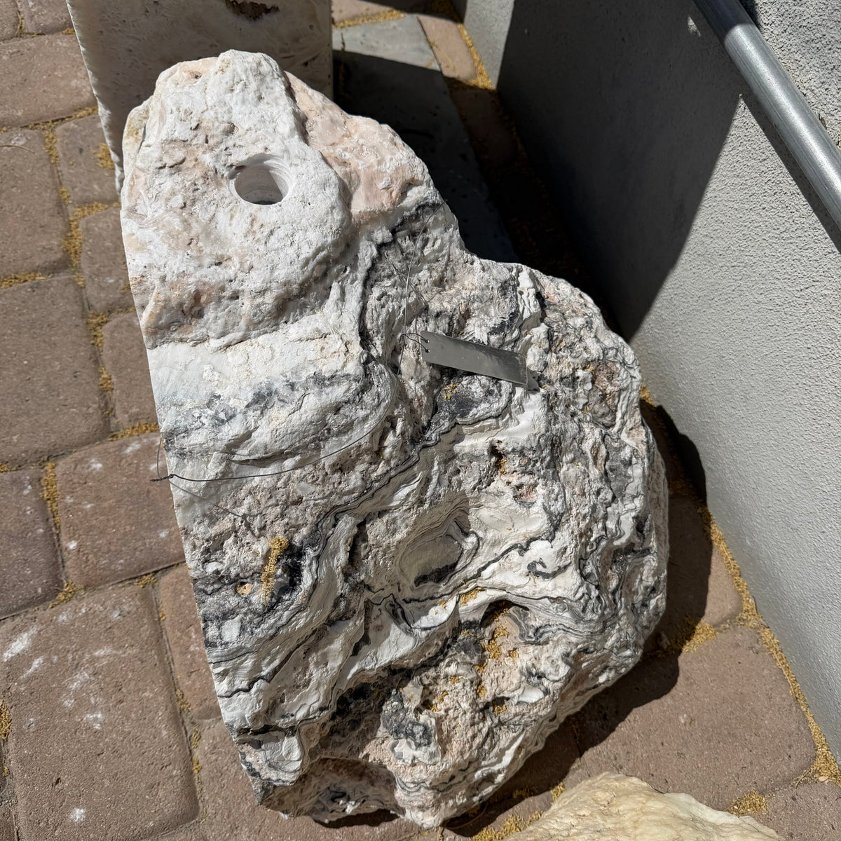 Top view of the White Zebra fountain boulder's cut side with drilled fountain hole and metal tag