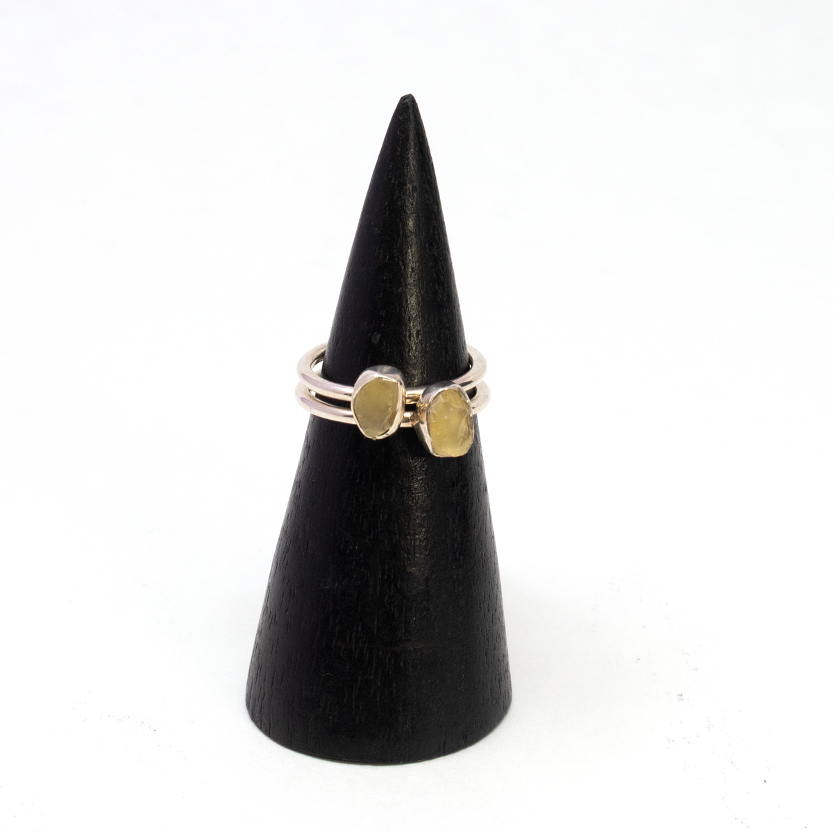 Two Egyptian tektite rings with rough freeform stones in silver bezels shown side by side