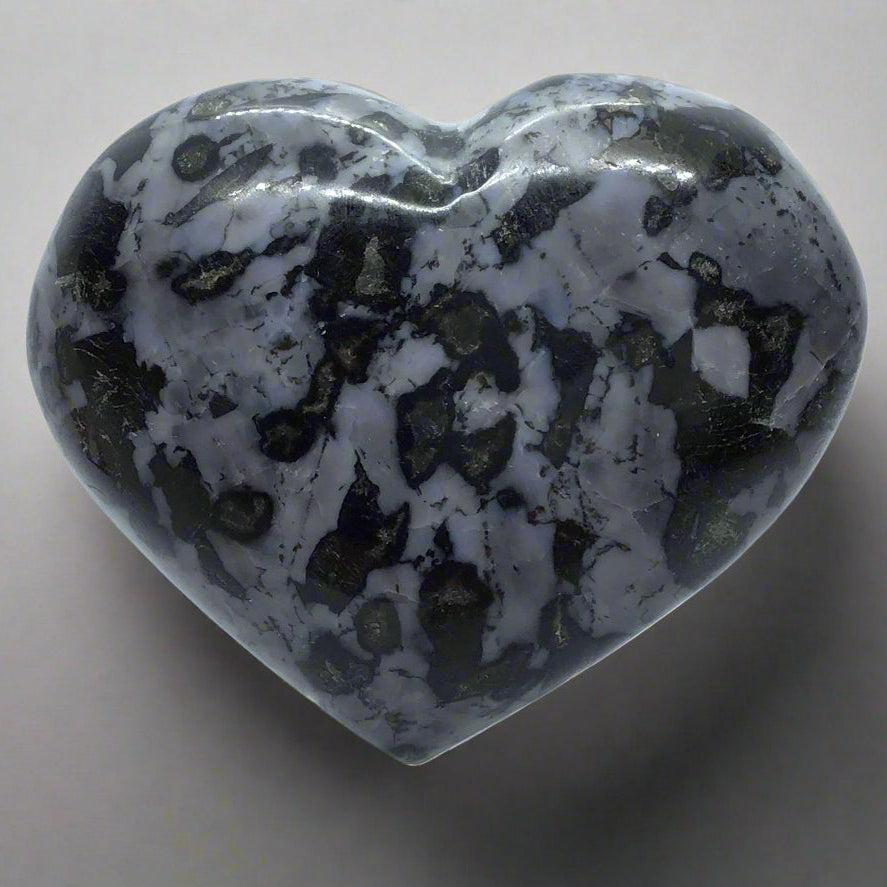 Indigo Gabbro heart with gray and black patterns, displayed on a clear Lucite stand.