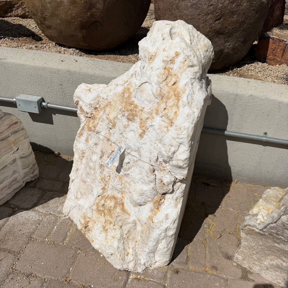 Sunset fossil onyx fountain stone standing upright on pavers with a cream and tan natural rough face