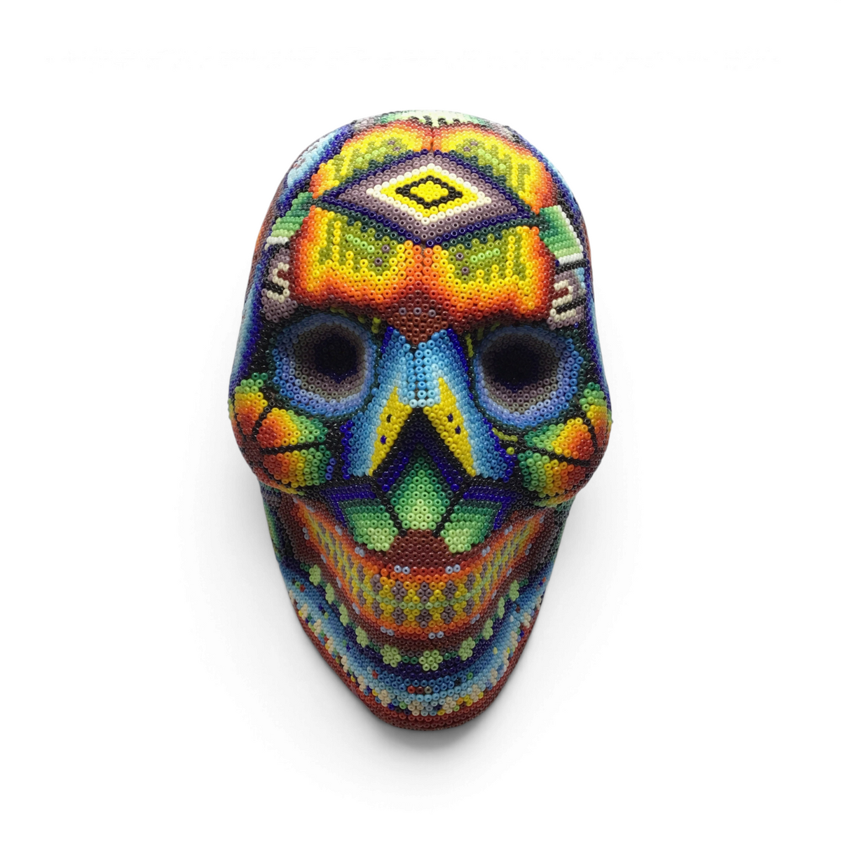 Huichol beaded skull with hexagonal patterns in warm red tones, front view on stand