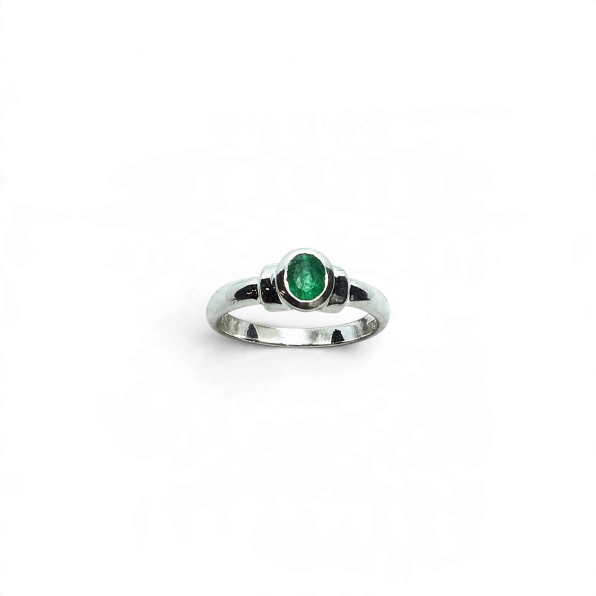 Rare Earth Gallery emerald ring featuring a bezel set faceted oval stone with step shoulder detail on a silver band.