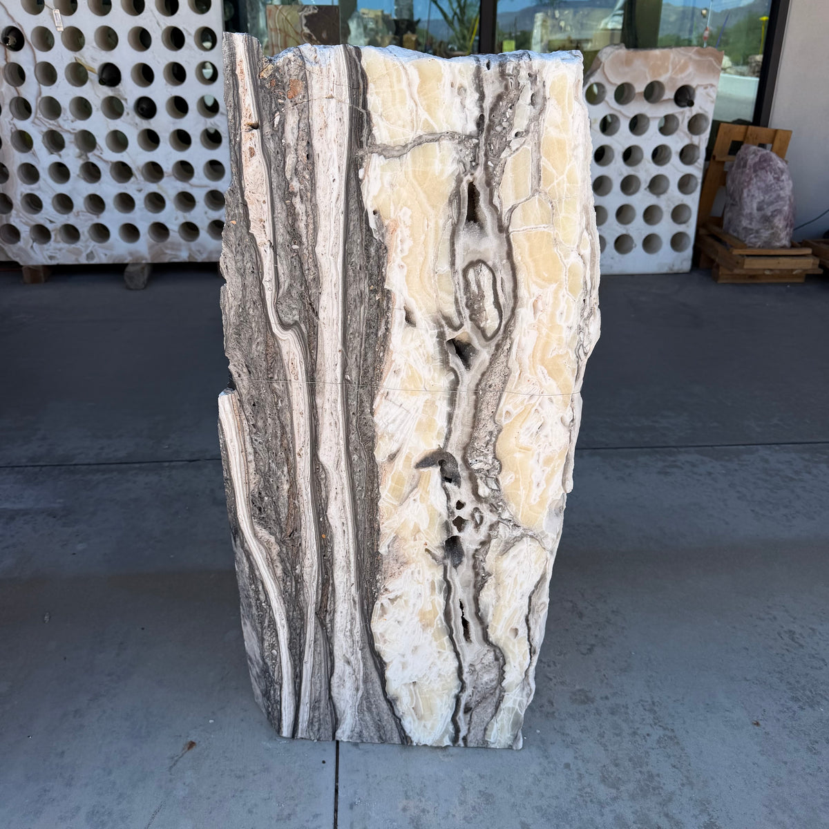 Zebra onyx fountain slab with cream, gold and gray banding standing upright on the gallery patio
