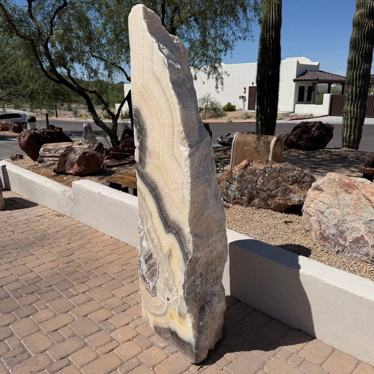 Yellow orange cosmic zebra onyx tapered pillar fountain with golden banded layers in a desert landscape
