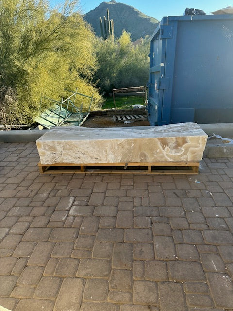 Amber onyx fountain block resting on a wooden pallet outdoors, desert mountain and saguaro backdrop