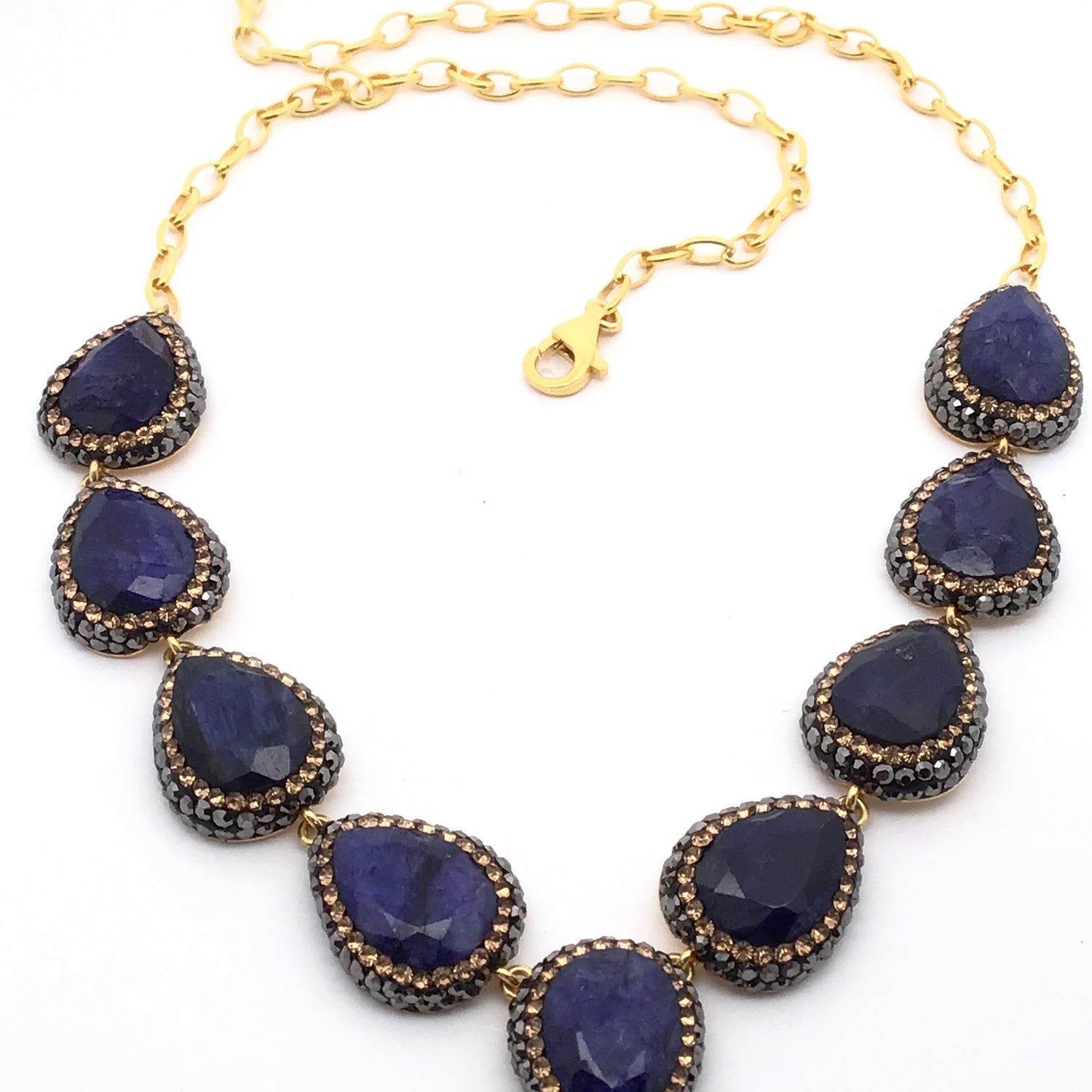 Necklace with blue teardrop-shaped pendants and gold chain on a white background