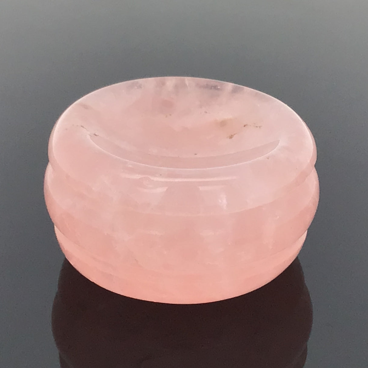 Rose quartz gemstone sphere stand disc with concave cradle, photographed on a soft gray gradient