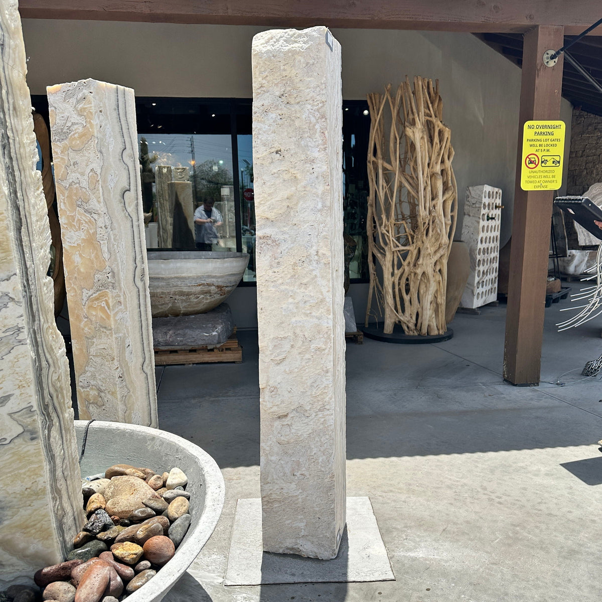 Tall zebra fossil onyx pillar fountain under the gallery patio among other onyx pillars and stone basins