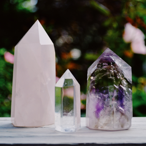 Three crystal towers on a wooden surface with a blurred natural background