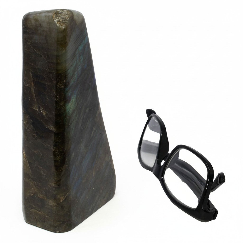 Rare Earth Gallery polished labradorite freeform stone with iridescent blue and gold flashes next to black glasses