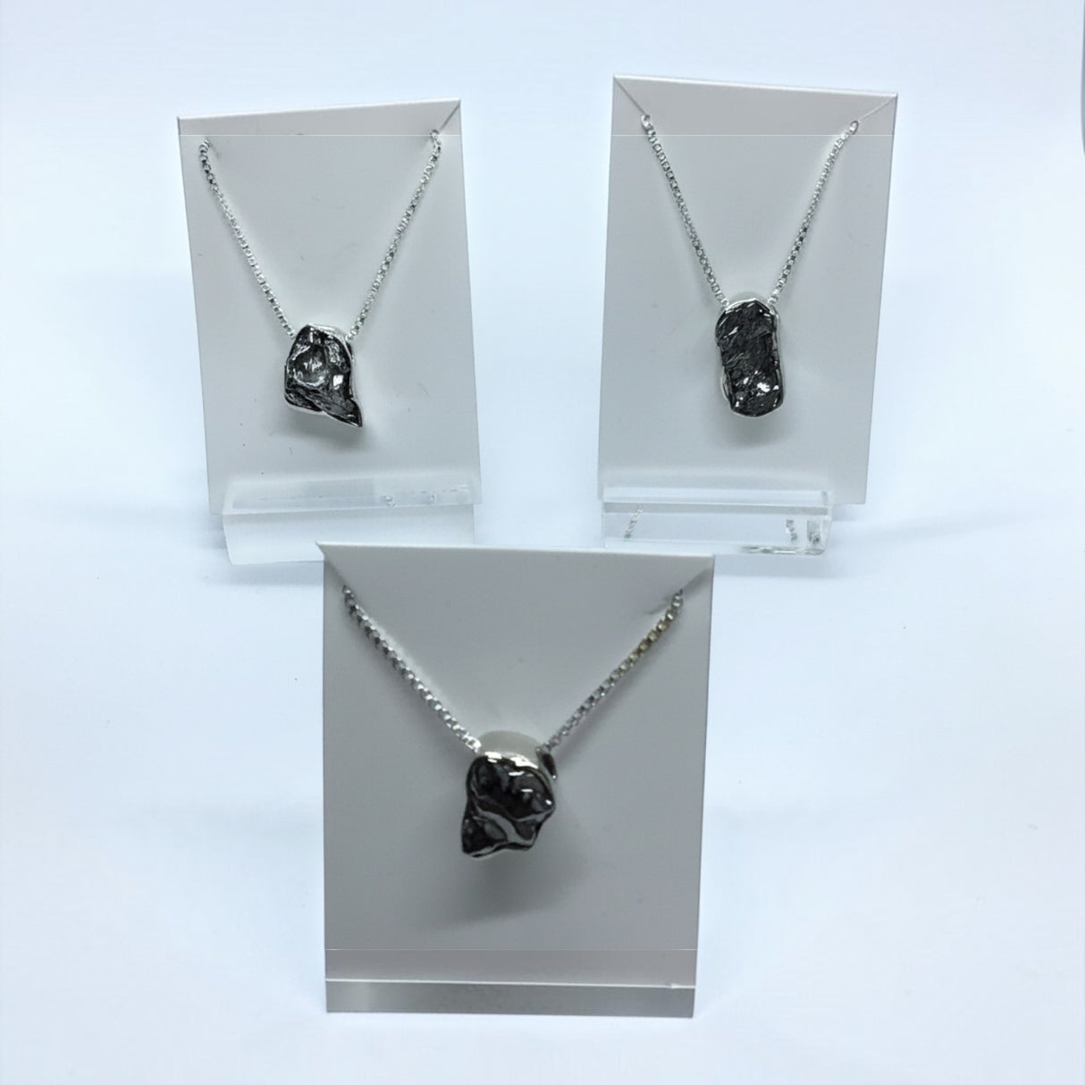 Rare Earth Gallery Campo De Cielo meteorite necklaces in freeform silver bezels on delicate silver box chains.
