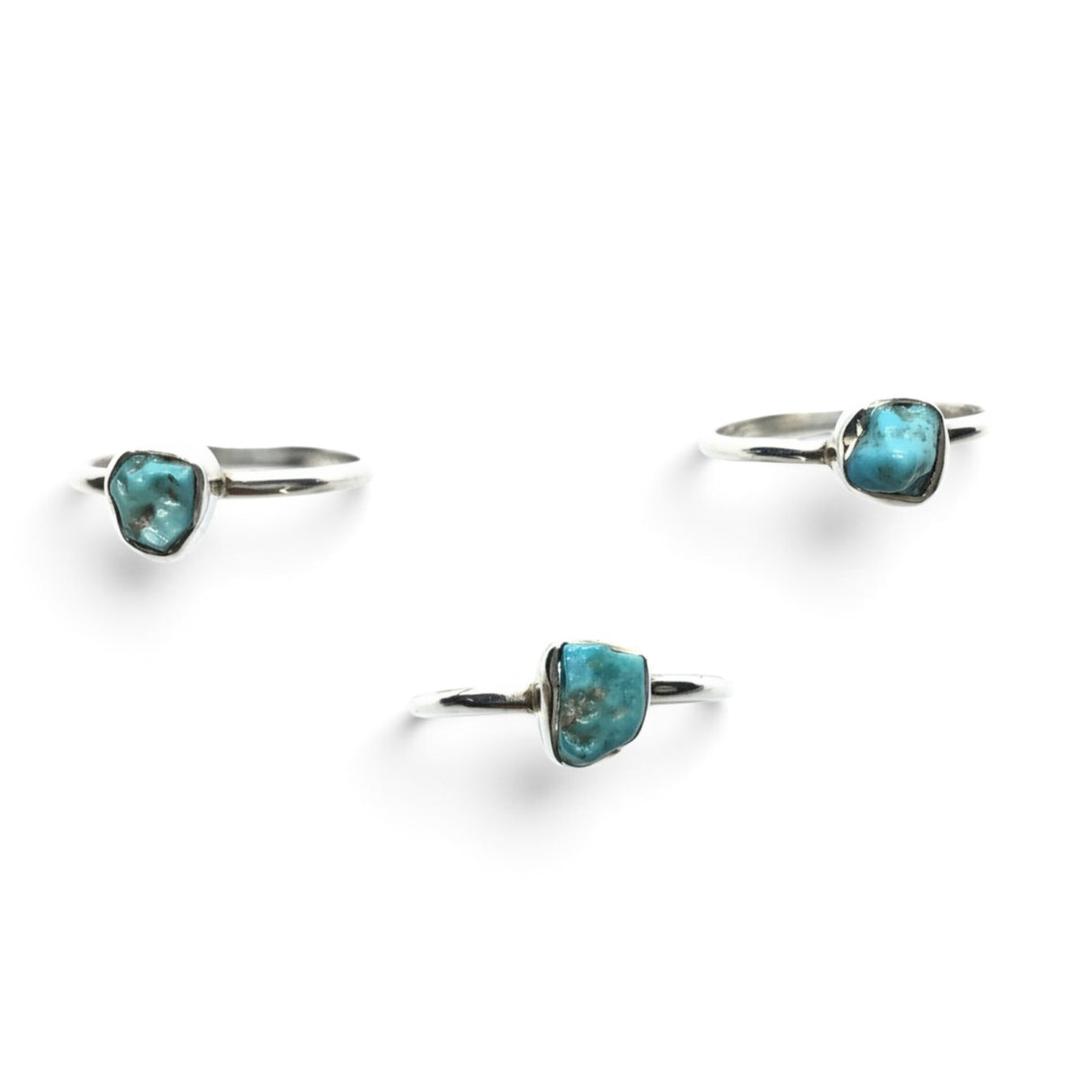 Rare Earth Gallery turquoise nugget dot rings with round silver bands arranged on a white background