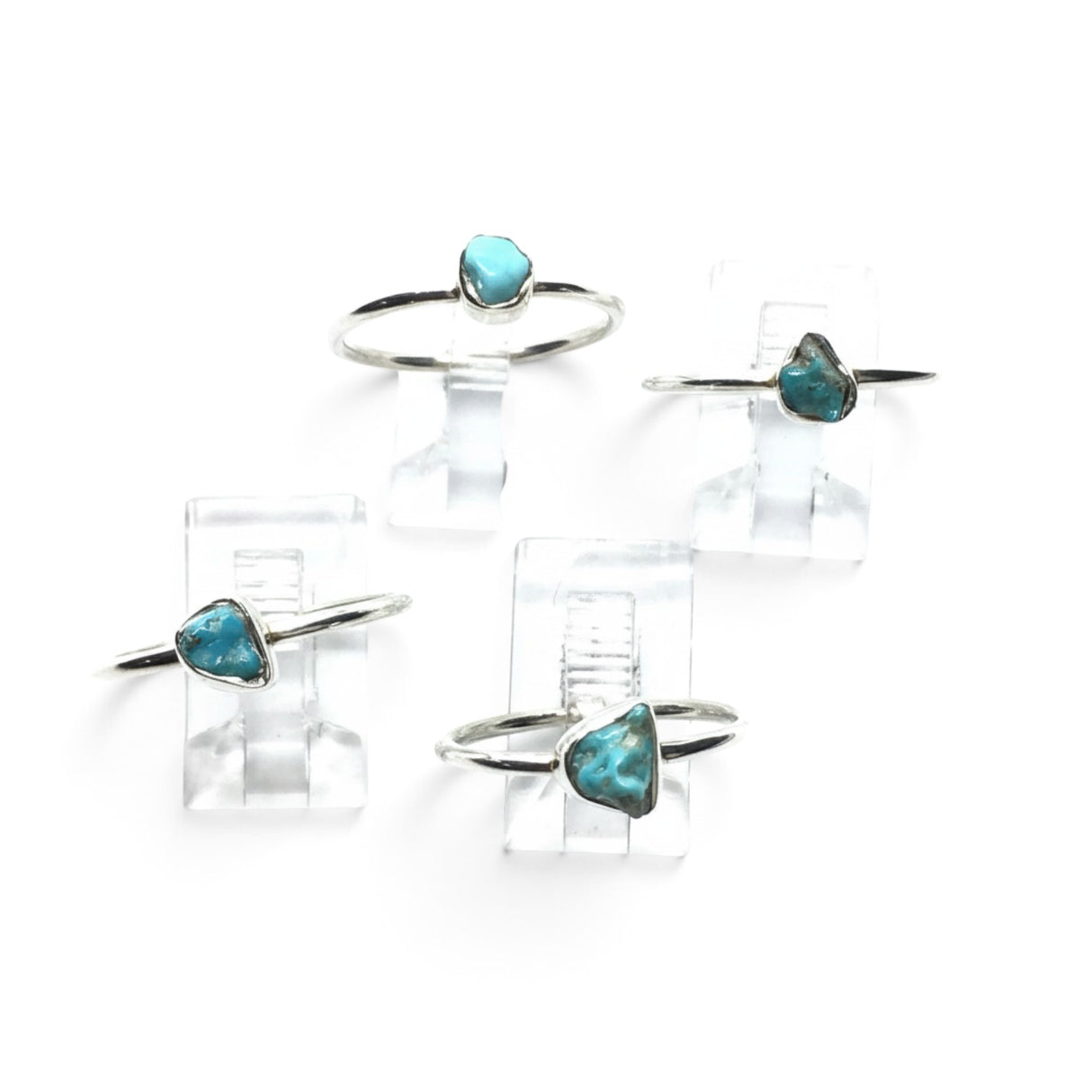 Rare Earth Gallery turquoise nugget rings with round silver bands displayed on clear stands