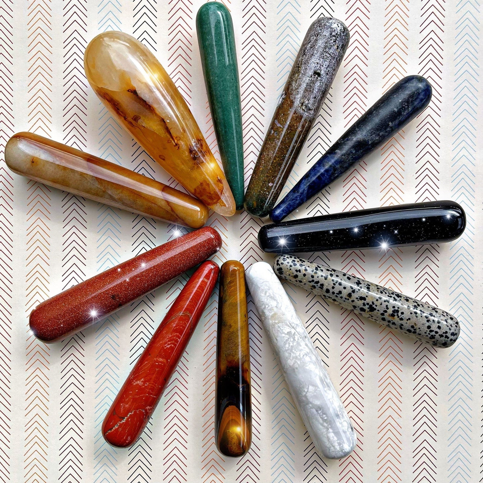 Crystal massage wands in assorted polished stones, arranged in a circular pattern