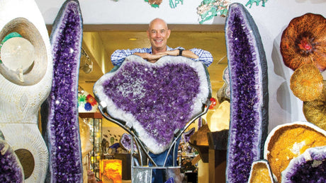 Owner of Rare Earth Gallery Wayne Helfand stands behind a life-sized amethyst geodes surrounded by other crystals and glass art.