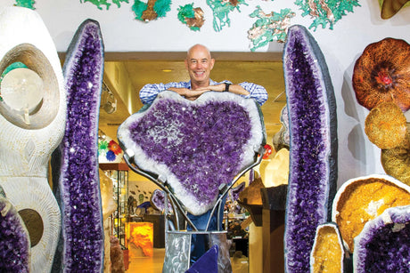 Wayne, owner of Rare Earth Gallery, stands with sparkling amethyst geodes and fine crystal home accents at Rare Earth Gallery in Arizona.
