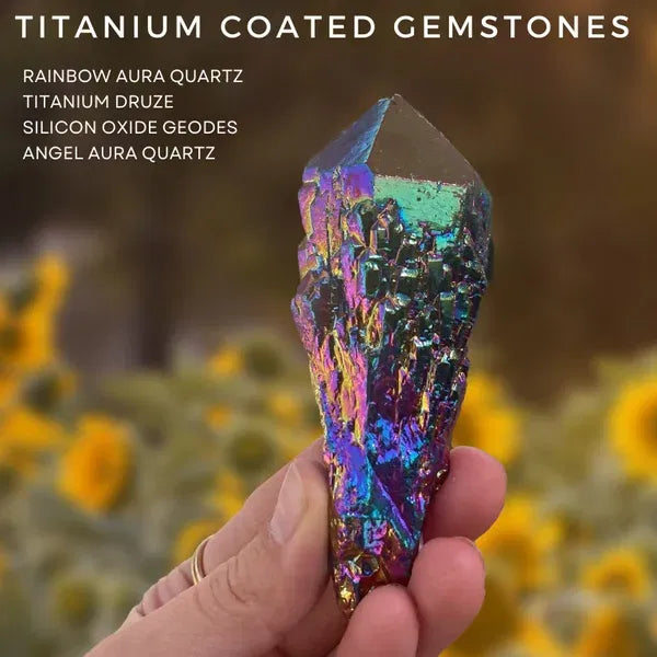 Titanium coated gemstones, an iridescent rainbow-coated quartz point held in a hand before a field of sunflowers