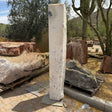 Zebra Fossil Onyx pillar fountain standing upright in a desert stone yard beside petrified wood logs and saguaro