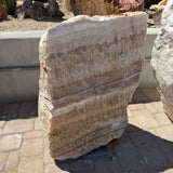 Serpentine onyx layered boulder fountain, cut face showing cream and tan bands, on outdoor pavers