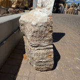 Side profile of serpentine onyx boulder fountain with natural layered surface in a stone yard