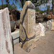 Cosmic Orange Zebra Onyx fountain column with tan, cream and charcoal banding standing in an outdoor stone yard