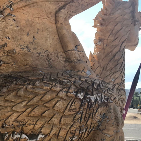 Close-up of tan travertine dragon's scaled body and wing showing natural quartz pockets