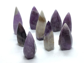 Trapiche Amethyst Flame - small, polished purple crystals with pointed tips arranged in a cluster on a white background.