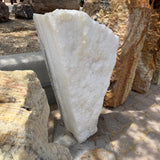 Side profile of the Ice White Onyx Fountain showing its angular saw-cut edge beside petrified wood pieces