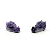 Two lilac lepidolite dragon skull carvings facing each other, mottled purple stone