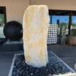 White crystal and gray onyx band fountain, cream travertine pillar set in a black river-rock basin