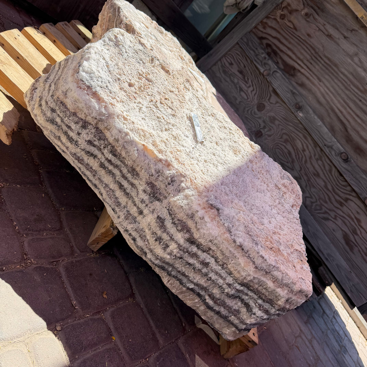 Red Zebra Onyx fountain block on a wood pallet, striped edge beside a rough cream and blush face