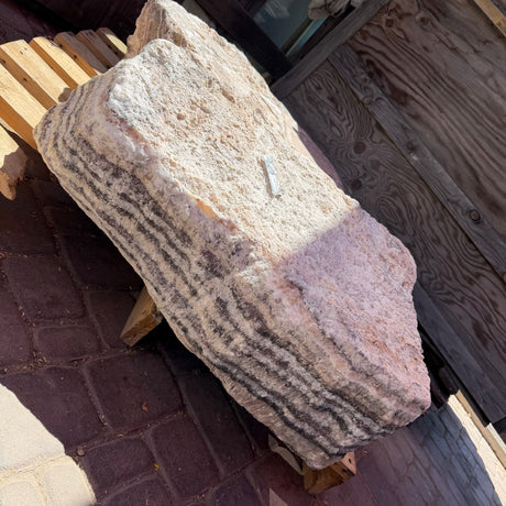 Red Zebra Onyx fountain block on a wood pallet, striped edge beside a rough cream and blush face