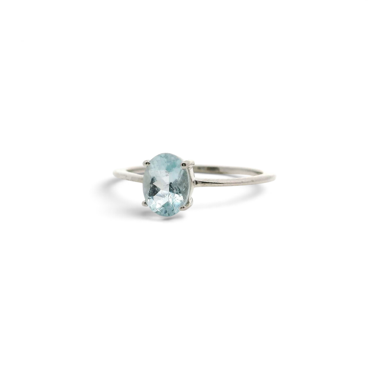 Aquamarine ring with a faceted oval pale-blue stone prong set on a slim sterling silver band