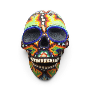 Huichol beaded skull front view with green and orange peyote patterns and white beaded teeth