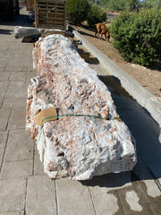 Zebra fossil onyx pillar fountain with rough white and rust crystalline surface, strapped and staged on pavers