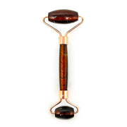 Red tiger's eye face roller with deep reddish-brown chatoyant bands on rose gold rollers, front view