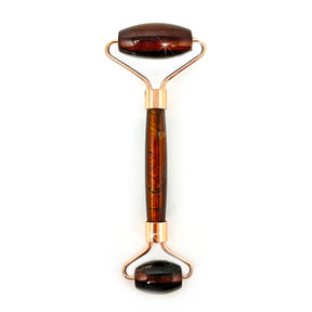 Red tiger's eye face roller with deep reddish-brown chatoyant bands on rose gold rollers, front view
