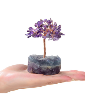 Purple amethyst beaded gemstone tree on fluorite base held in a hand for scale