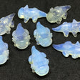 Opalite axolotl carvings with milky blue glow, group of ten shown on black surface