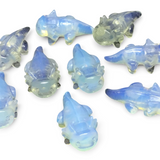 Opalite axolotl carvings with milky blue glow, group of ten shown on black surface