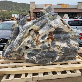 Large decorative stone sculpture on a wooden pallet with a store and cars in the background