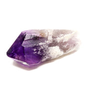 Bahia amethyst crystal point with vivid purple faceted tip and white-crusted smoky pale body