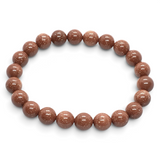 Rare Earth Gallery 8mm round red goldstone beaded bracelet with a polished, glittering finish on an elastic cord.