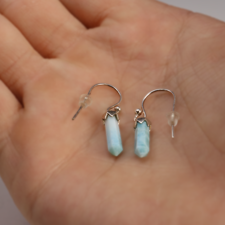 Larimar terminated point drop earrings capped in silver, pale blue, held in hand